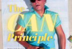 Promotional poster on a beach towel showing a man in a turquoise shirt and rubber-ducky shorts, with large yellow text reading 'The CAN Principle' and spray cans scattered around.