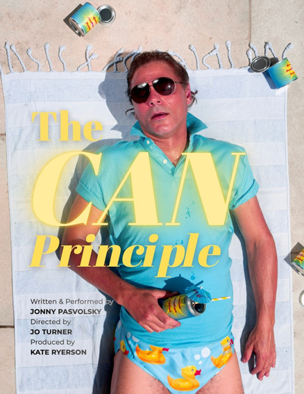 Promotional poster on a beach towel showing a man in a turquoise shirt and rubber-ducky shorts, with large yellow text reading 'The CAN Principle' and spray cans scattered around.